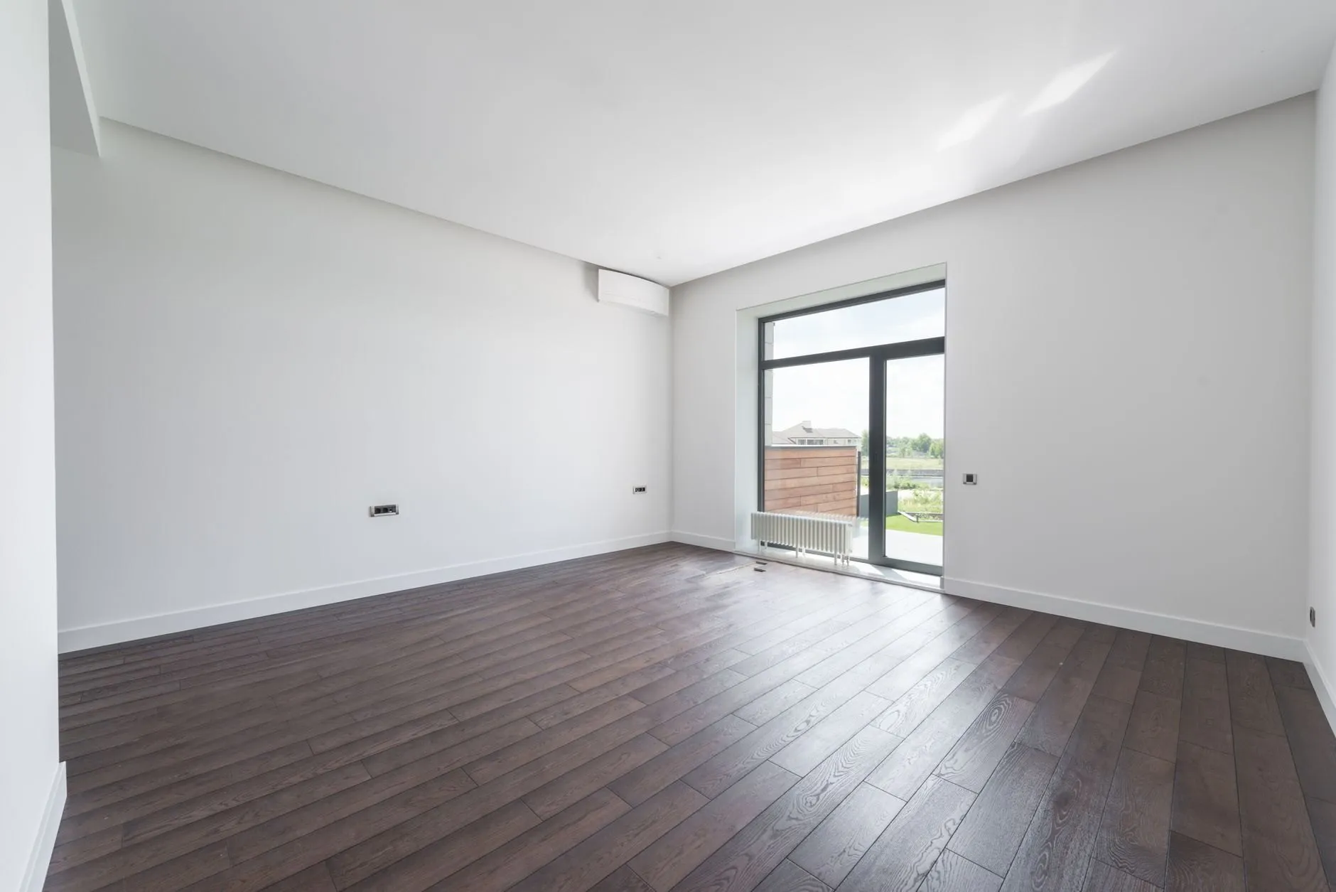 An empty, swept room with a dark wood floor after a move