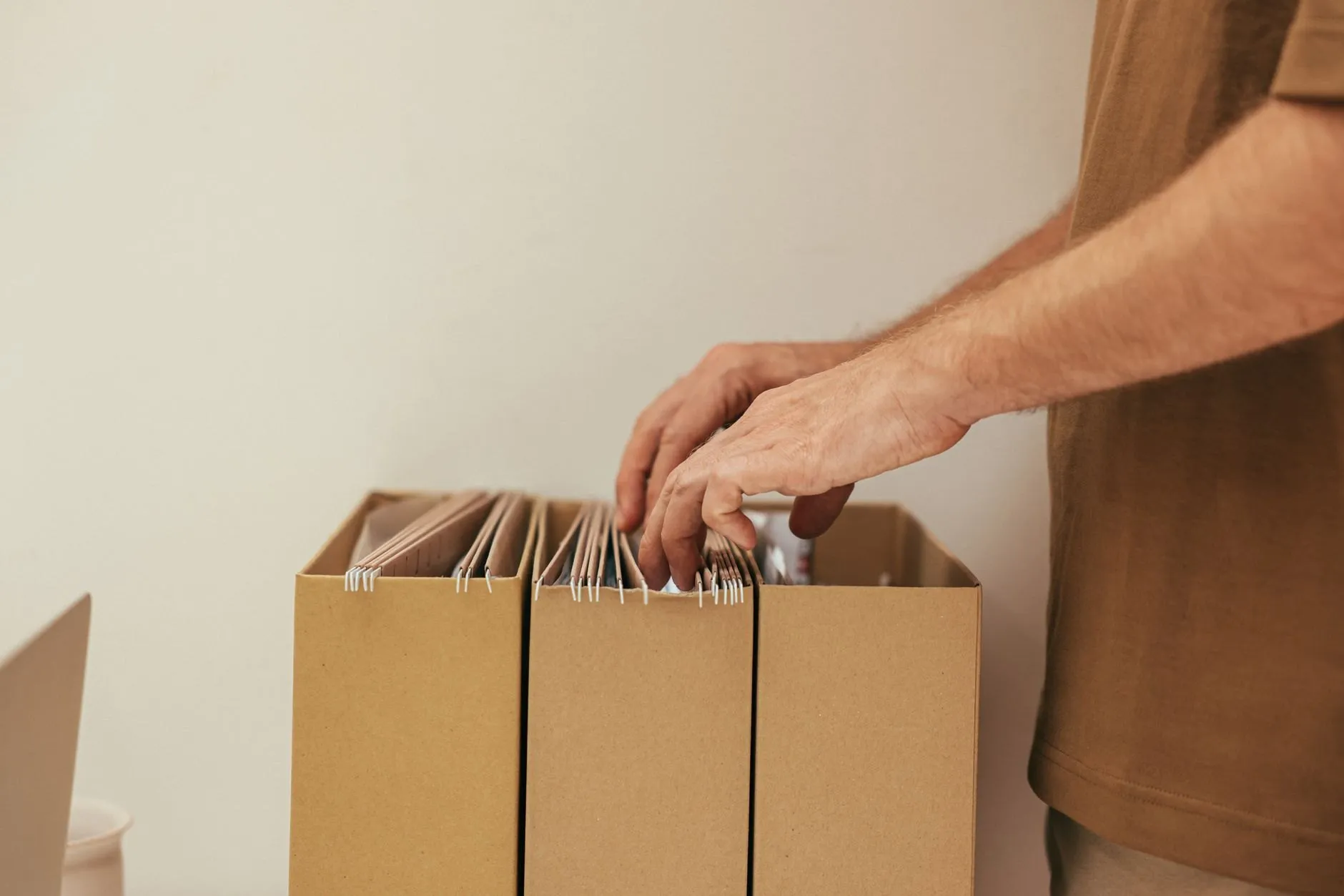 Hands packing hanging files into a plain cardboard crate