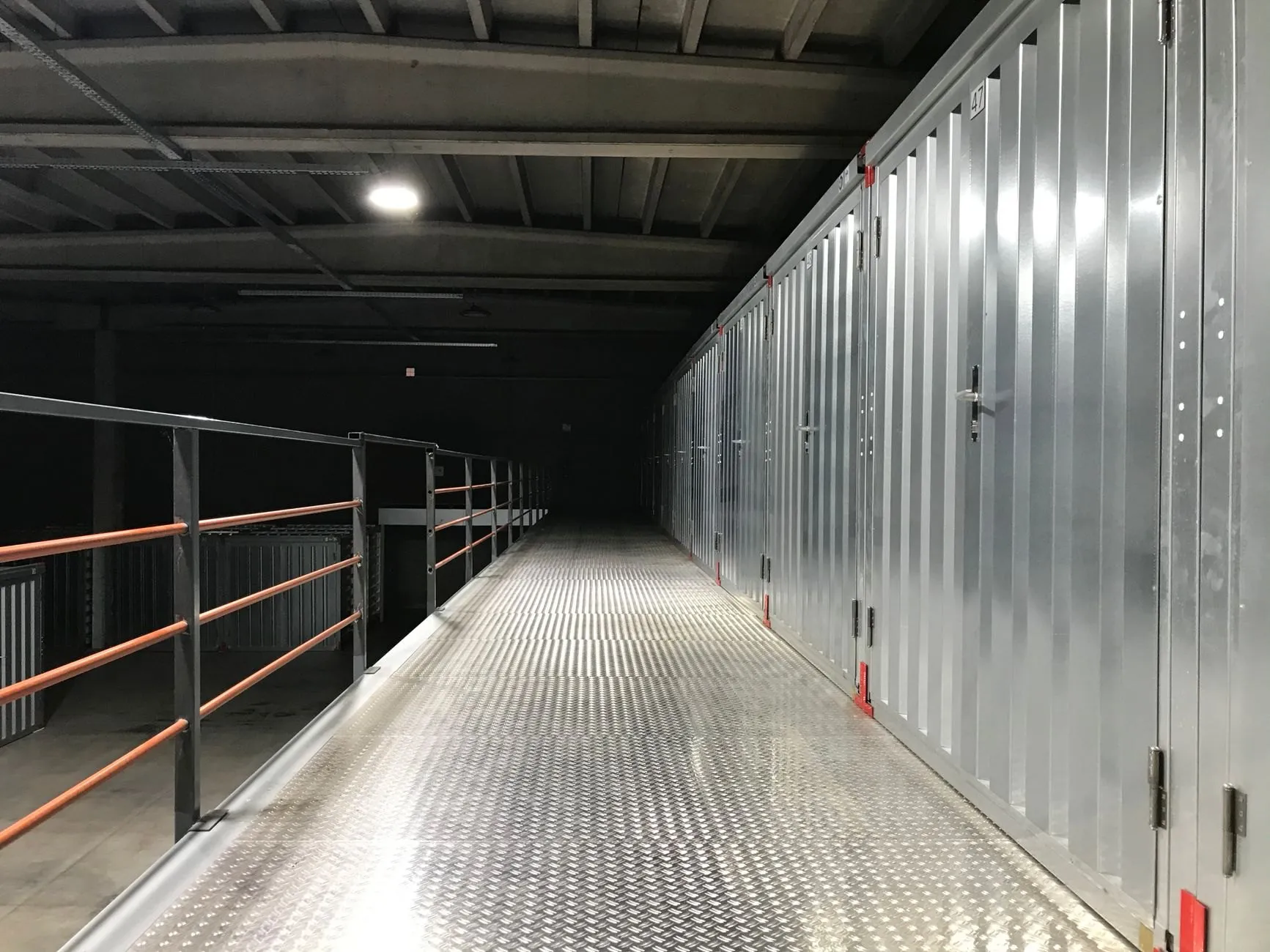 A quiet walkway past closed storage units in a warehouse